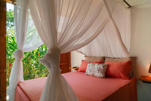a bedroom with a canopy bed with red pillows at Casa Canoa - Praia de Algodões in Marau