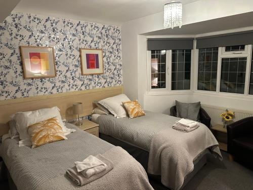 two beds in a room with blue and white wallpaper at Station Approach B&B Boutique Stays in Solihull