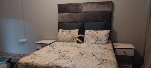 a bedroom with a bed with a headboard and pillows at Green Escape Cottage Guesthouse in Albert Falls