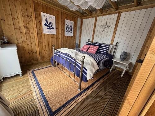 a bedroom with a bed in a wooden room at Tregantle Farm Eco GLAMPSITE in Torpoint