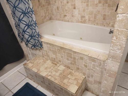 a bath tub in a bathroom with a tile floor at Pure Country, plenty of space & trees, relaxing! in Lumberton