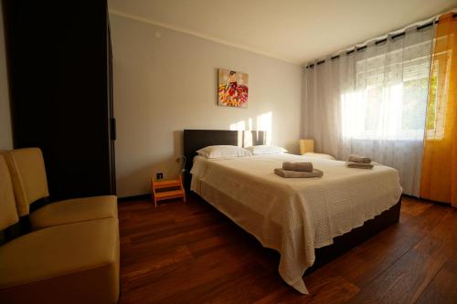 a bedroom with a bed and a chair and a window at B side in Fažana