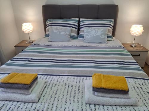 a bedroom with a bed with towels and two lamps at Apartmani Mirela in Krk