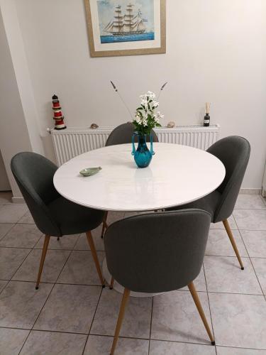 a white table with four chairs and a vase with flowers at Angela's house in Galaxidhion
