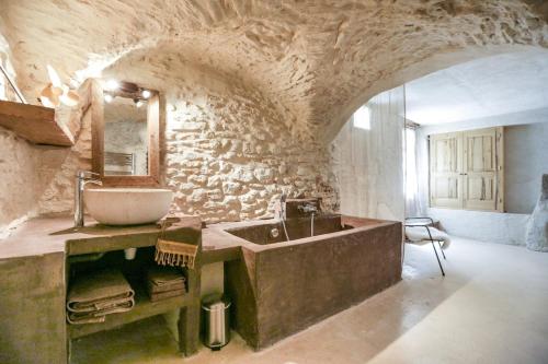 une salle de bain avec un lavabo et un mur en pierre dans l'établissement La Grande Bergerie, à Saint-Saturnin-lès-Apt