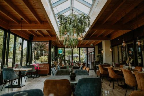 a restaurant with tables and chairs and a glass ceiling at Hotel Jachtlust in Borne