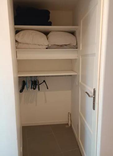 un placard avec une porte blanche et des oreillers dans l'établissement Jolie logement 4pers Lacanau océan, à Lacanau