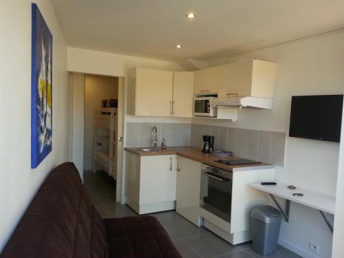 une cuisine avec des armoires blanches et un canapé dans une pièce dans l'établissement Jolie logement 4pers Lacanau océan, à Lacanau