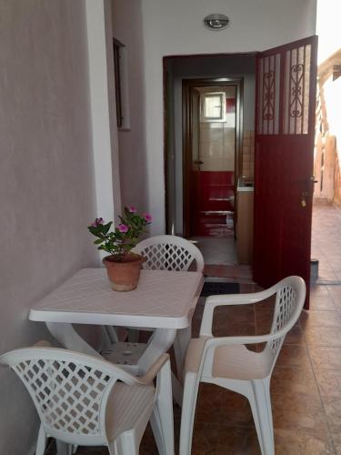 biały stół i krzesła z doniczkową rośliną na nich w obiekcie Flor Apartament w Sarandzie