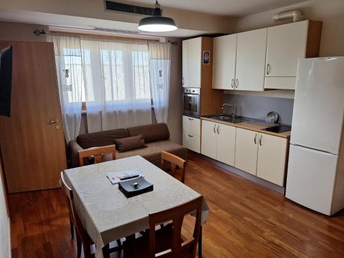 a kitchen and a living room with a table and a refrigerator at Solaria House appartamenti con cucina a 200 MT dalla Basilica di Padre Pio e 600 MT dall'ospedale Casa Sollievo della Sofferenza in San Giovanni Rotondo