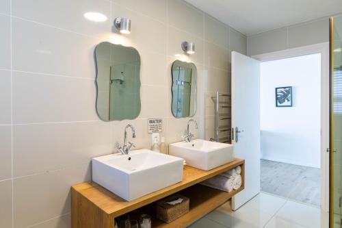 two sinks in a bathroom with two mirrors at Dune Beach House in Wilderness