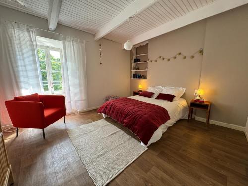 a bedroom with a large bed and a red chair at Magnifique Gîte 4 à 10 personnes in Nages