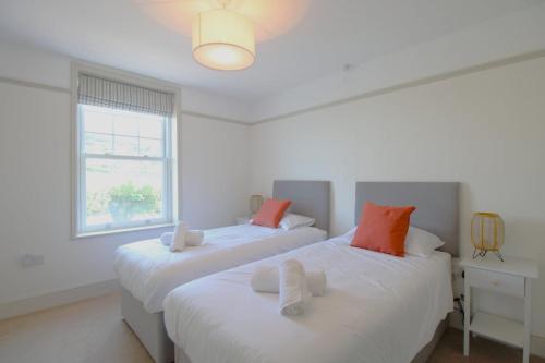 Dos camas en una habitación blanca con ventana. en Beachfront Luxury Edwardian Retreat With Sea View, en Combe Martin