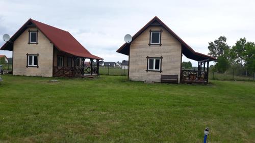 two houses in a field with a grass yard at Domki pod Klekotkiem in Smołdziński Las