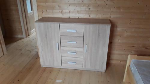 a small white cabinet in a room with wooden walls at Domki pod Klekotkiem in Smołdziński Las