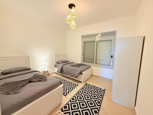 a bedroom with two beds and a window and a chandelier at Elegant 3BR Chalet Steps from the Pool in Ain Sokhna