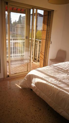 - une chambre avec un lit et une porte donnant sur un balcon dans l'établissement 54m2, clim, T2, centre BANDOL, terrasse, TOUT A PIED, à Bandol