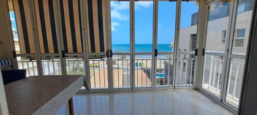 a room with large windows and a view of the ocean at CARIBE Apartamento in Oropesa del Mar