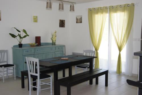 une salle à manger avec une table noire et des chaises blanches dans l'établissement Vacances océan, à Vensac