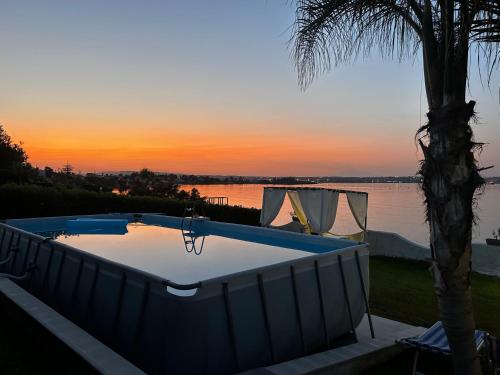 a swimming pool with a palm tree next to a body of water at Casa con piscina e vista mare dal giardino in Fanusa