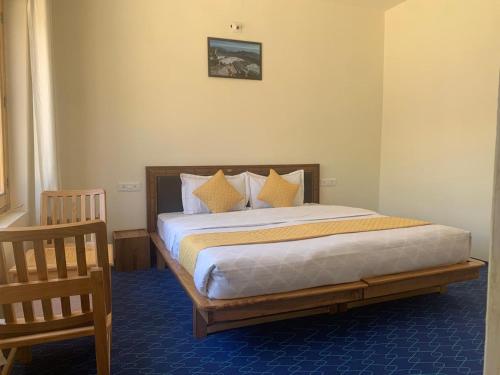 a bedroom with a large bed with yellow pillows at De Khar Guest House in Leh