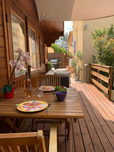a wooden table with a plate of food on a deck at CHALET, PISCINE, JARDIN CLOTURE, ANIMAUX Acceptés in Saint-Maximin-la-Sainte-Baume