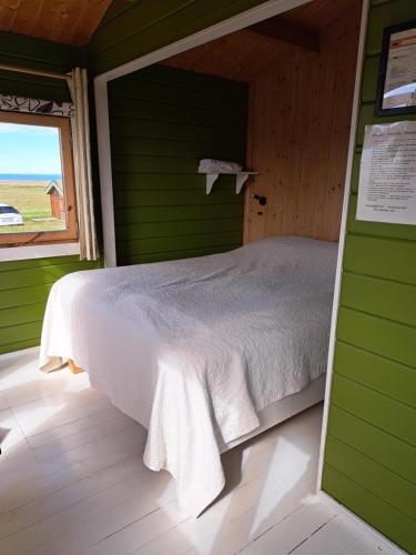 Posto letto in camera verde con finestra di Guesthouse Hof a Hofgarðar