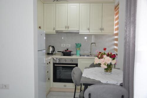 a kitchen with a table with a vase of flowers on it at Apartament Cela in Çorovodë
