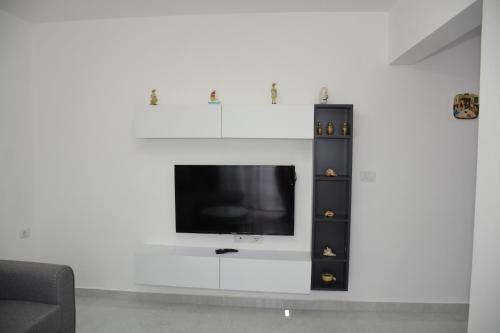 a living room with a tv on a white wall at Apartament Cela in Çorovodë