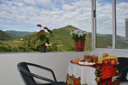 a table with food and a view of a mountain at Apartament Cela in Çorovodë