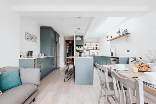 a kitchen with blue cabinets and a table and chairs at Salterns House - Coastal Escape near Sandbanks in Parkstone