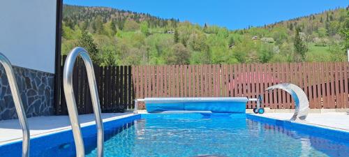 a swimming pool with blue water in front of a fence at Hotel & Apartments G S in Mykulychyn