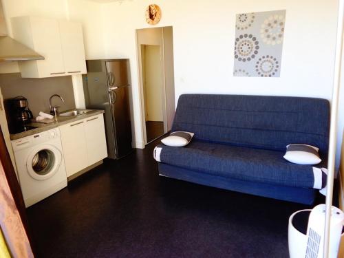 un salon avec un canapé bleu et une cuisine dans l'établissement Studio Héliopolis E1 - 2 personnes, au Cap d'Agde