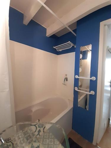 La salle de bains est pourvue d'une baignoire et d'un mur bleu. dans l'établissement Maisonnette avec terrasse à 300m de la plage 2 étoiles, à Saint-Georges-de-Didonne
