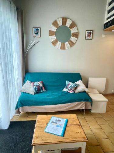 un salon avec un canapé bleu et une table dans l'établissement Maisonnette avec terrasse à 300m de la plage 2 étoiles, à Saint-Georges-de-Didonne
