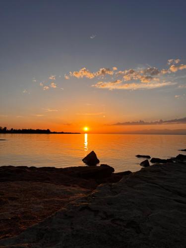a sunset over a body of water with rocks at Ak-keme in Tossor