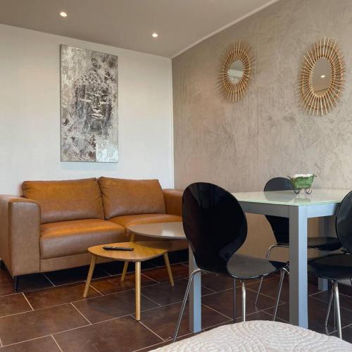un salon avec un canapé, une table et des chaises dans l'établissement Studio BROWN Héliopolis D 29 - Luxe - 2 personnes, au Cap d'Agde
