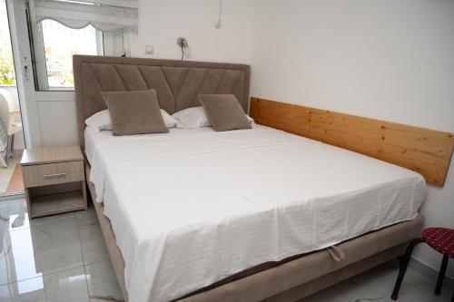 a bedroom with a large white bed with a wooden headboard at apartmani DENI in Donji Štoj