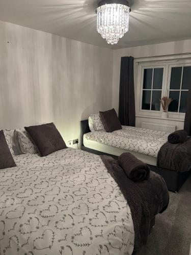 a bedroom with two beds and a chandelier at 3BR House in Newton-Le-Willows - Sleeps 6 in Earlestown