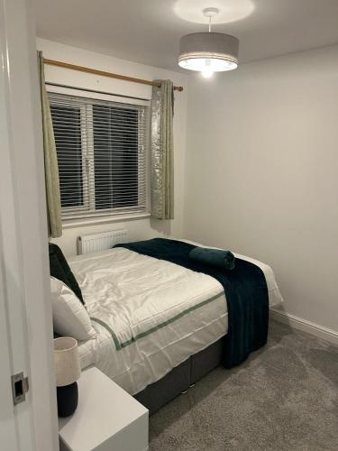 a bedroom with a bed with a blue blanket on it at 3BR House in Newton-Le-Willows - Sleeps 6 in Earlestown