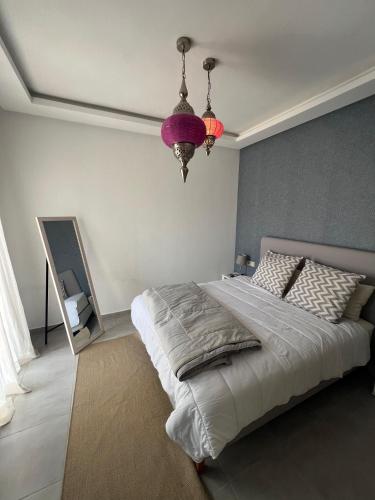 a bedroom with a large bed and a purple chandelier at appartement costa mar martil avec piscine in Martil