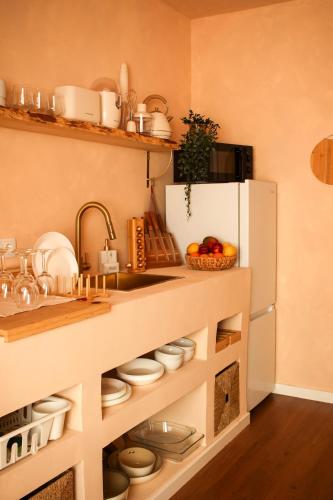 a kitchen with a counter with dishes and a refrigerator at Memories by the Sea - Margarida do Mar in Costa da Caparica