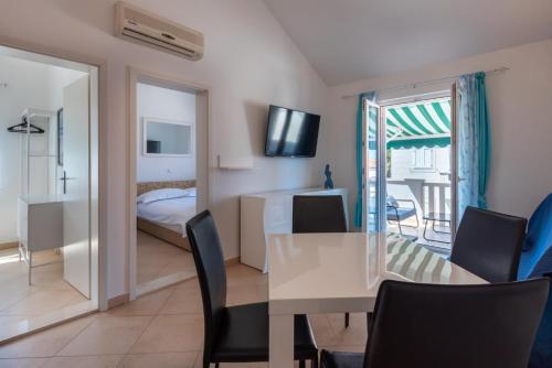 a dining room with a table and chairs and a bedroom at APARTMENTS BRUNO 3 - two-room penthouse apartment - wonderful view of the sea - the best location, first row to the beach - 10 minutes from Supetar ferry port - free secured parking - facilities nearby in Sutivan