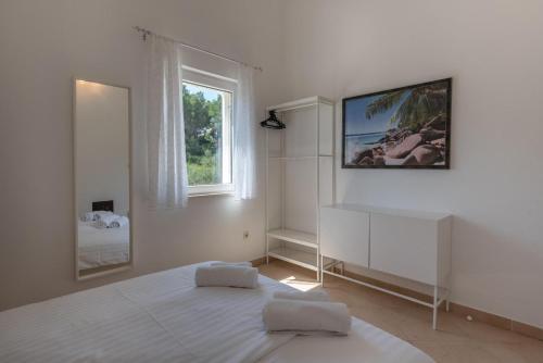 a white bedroom with a bed and a window at APARTMENTS BRUNO 3 - two-room penthouse apartment - wonderful view of the sea - the best location, first row to the beach - 10 minutes from Supetar ferry port - free secured parking - facilities nearby in Sutivan