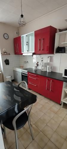 - une cuisine avec des placards rouges et une table dans l'établissement Villa Mon Repos 1, à La Bourboule