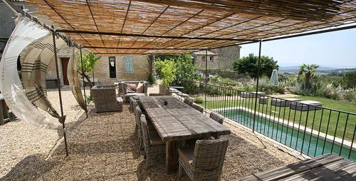 une terrasse avec une table en bois et une piscine dans l'établissement La Grande Bergerie, à Saint-Saturnin-lès-Apt