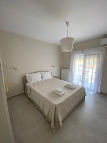 a white bedroom with a bed with two towels on it at Alion houses in Prinos