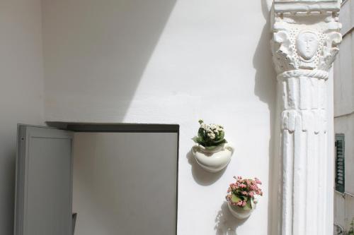 a wall with two flower pots and a column at Dimora il Capitello in Cisternino