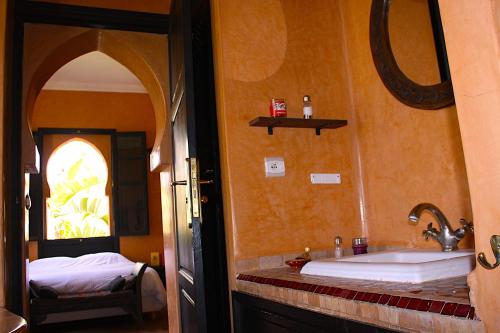 a bathroom with a sink and a bed in a room at Dar Mardan in El Aggada