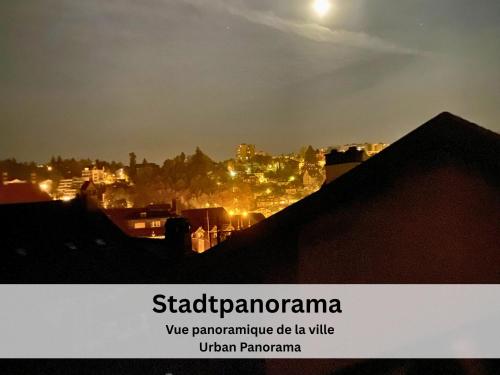 a view of a city at night with the moon at Maison de Castella next to Cathedrale in Fribourg